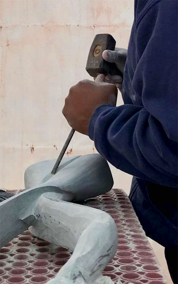 Hands using a hammer and chisel to carve stone