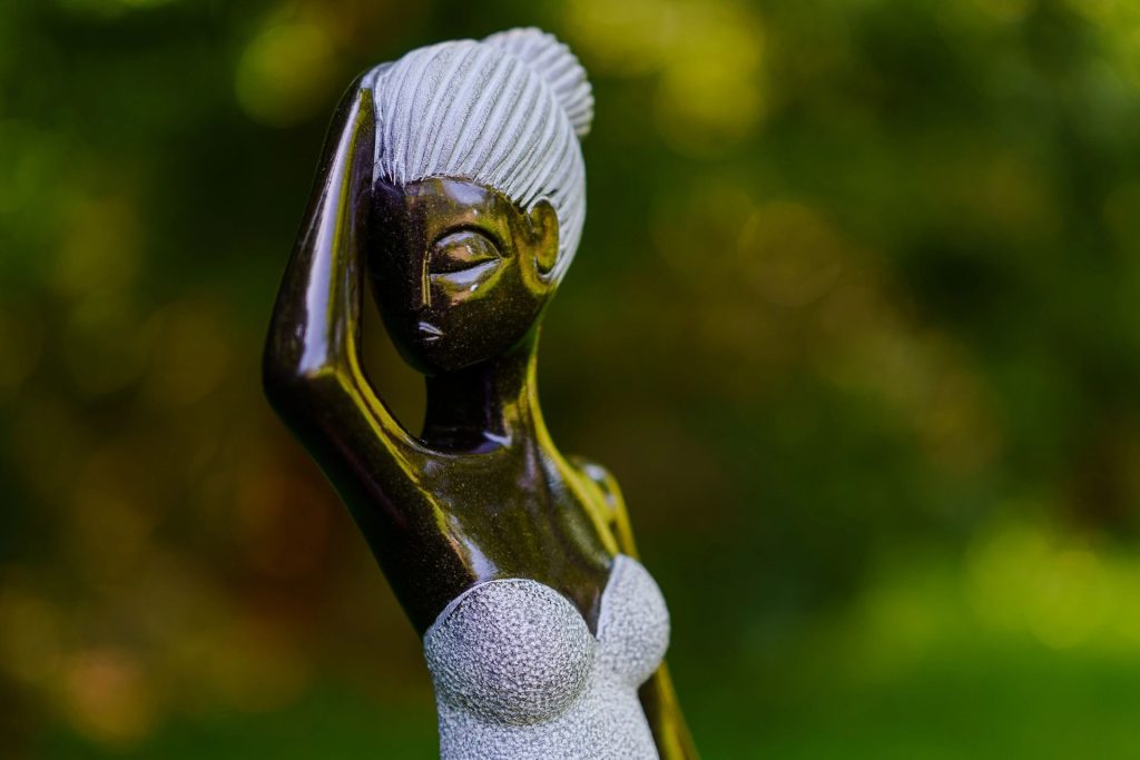 Polished stone sculpture of a woman displayed in a garden