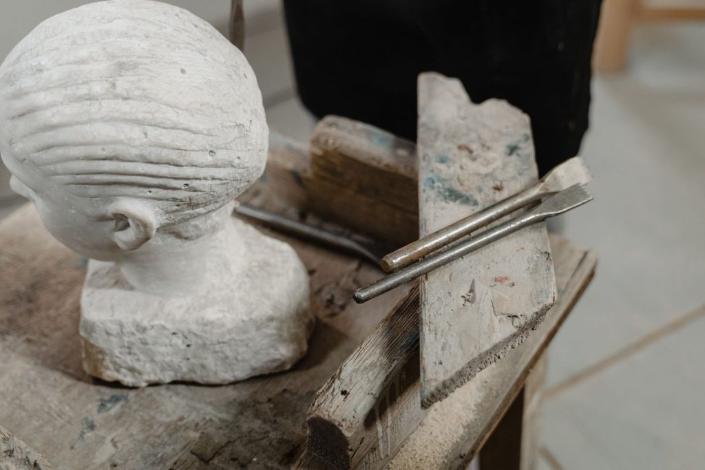Carved stone head with sculpting tools on a wooden table